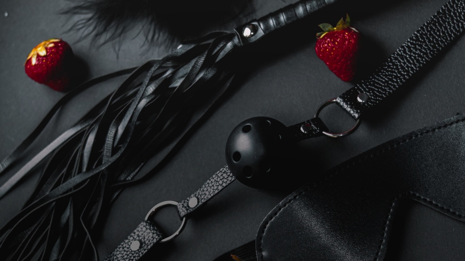 Spice rating vs star rating blog banner with dark romance elements like a leather whip and feathers.